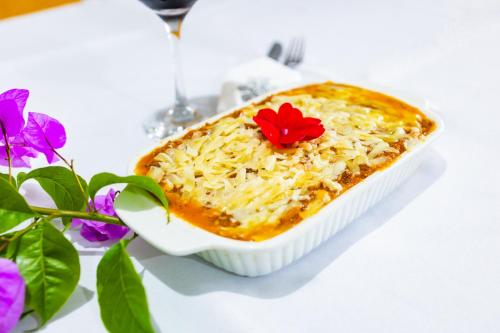 a white dish of food with a red flower on it at Putini Pousada e Hotel by OYO in São Roque
