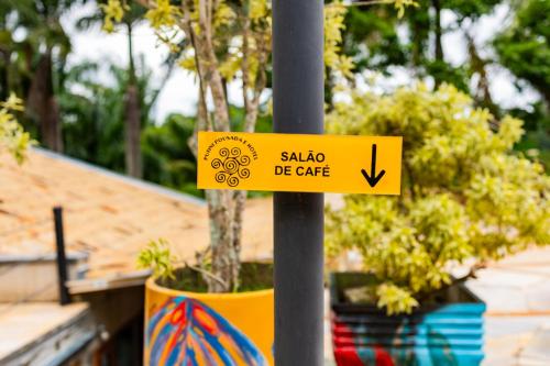 a yellow sign on a pole with a plant at Putini Pousada e Hotel by OYO in São Roque