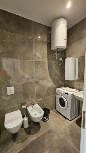 a bathroom with a toilet sink and a washing machine at Whisky Green Coast Hotel & Apartments in Palasë