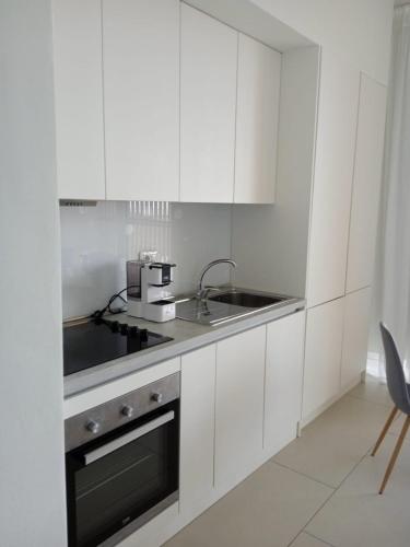 a white kitchen with a sink and a stove at Whisky Green Coast Hotel & Apartments in Palasë