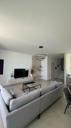 a living room with a couch and a tv at Whisky Green Coast Hotel & Apartments in Palasë