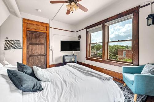 a bedroom with a bed and a tv and a blue chair at The Uptown Suite at The Historic Connely Harrington in Siloam Springs