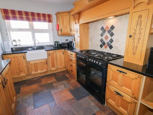 a kitchen with wooden cabinets and a black stove top oven at SeaShells in Coleraine