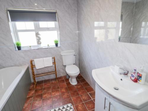 a bathroom with a toilet and a sink and a tub at SeaShells in Coleraine