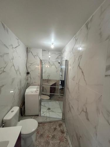une salle de bain blanche avec toilettes et douche dans l'établissement appart idéal en famille parking privé, à Drancy