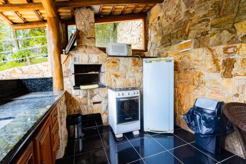 a stone kitchen with a refrigerator and a stove at Putini Pousada e Hotel by OYO in São Roque