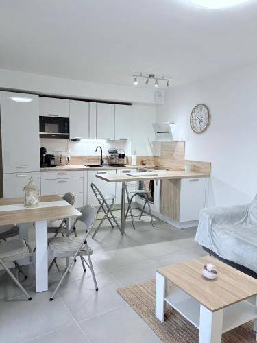 une cuisine avec des placards blancs, des tables et des chaises dans l'établissement Appartement climatisé avec jardin 4 personnes, au Plan-de-la-Tour