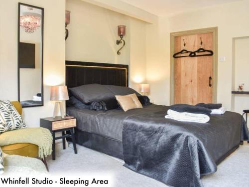 a bedroom with a large bed and a chair at Honeysuckle Cottage & Whinfell Studio in Penrith