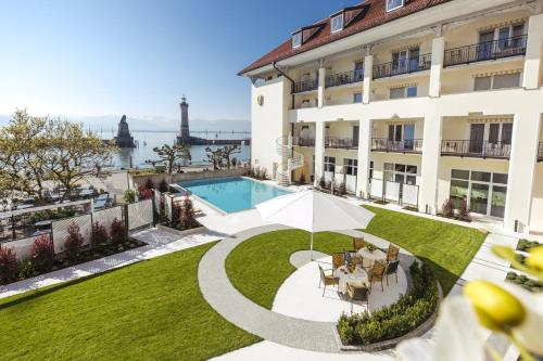 an image of a building with a swimming pool and a yard at Hotel Bayerischer Hof in Lindau