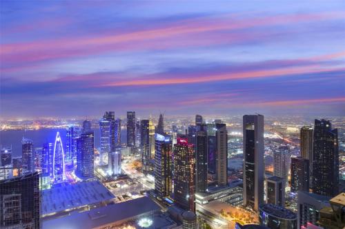 a night view of a city with tall buildings at Kempinski Residences & Suites, Doha in Doha