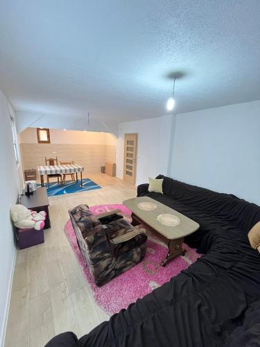 een woonkamer met een zwarte bank en een tafel bij Buća Potok Aurrora in Sarajevo