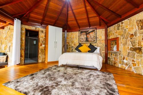 a bedroom with a bed and a stone wall at Putini Pousada e Hotel by OYO in São Roque