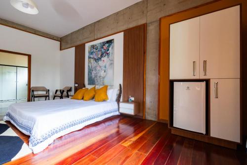 a bedroom with a large white bed and wooden floors at Putini Pousada e Hotel by OYO in São Roque