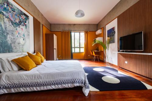 a bedroom with a large bed and a flat screen tv at Putini Pousada e Hotel by OYO in São Roque