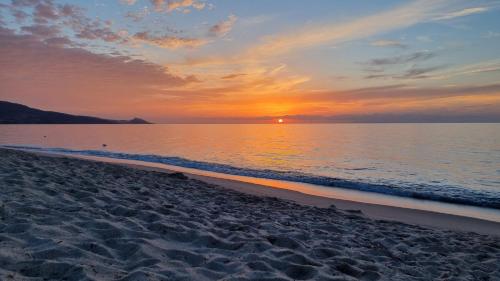 a sunset on a beach with the shoreline at Casa con terrazza nella Pineta in La Ciaccia