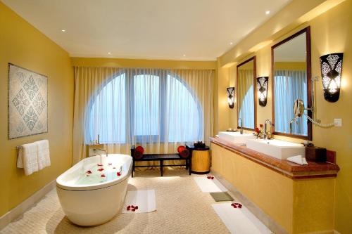 a bathroom with a large tub and a large mirror at Djibouti Palace Kempinski in Djibouti