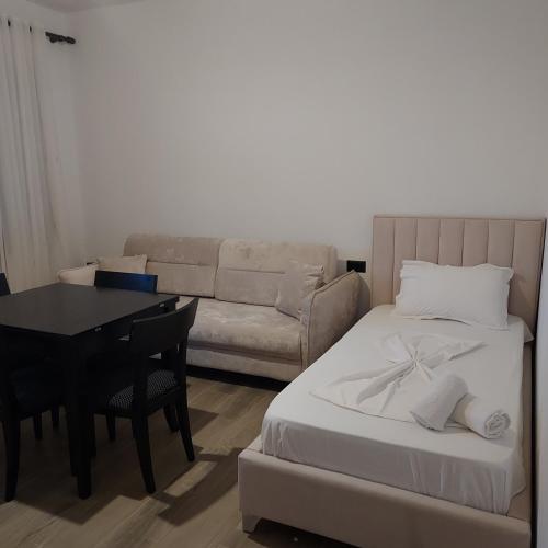 a room with a bed and a couch and a table at Vila Martini in Vlorë