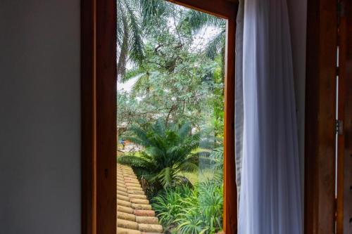 a sliding glass door with a view of a garden at Putini Pousada e Hotel by OYO in São Roque