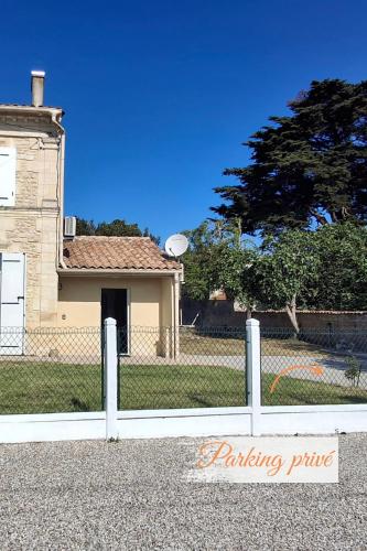 une clôture devant une maison avec un frisbee dans l'établissement Pierres d'Estuaire, à Valeyrac