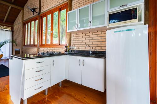 a kitchen with white cabinets and a brick wall at Putini Pousada e Hotel by OYO in São Roque