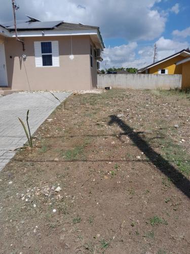 a shadow of a building and a house at C & J's Coco Manor Vacation Home in Old Harbour