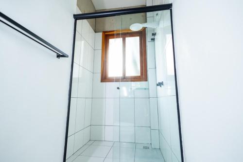 a shower with a glass door and a window at Putini Pousada e Hotel by OYO in São Roque
