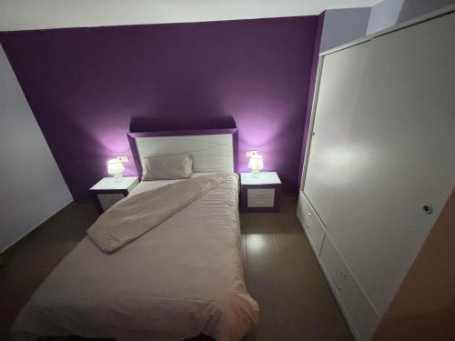 a bedroom with purple walls and a bed with two lamps at Appartement VILLAJOYOSA 98m2 PROCHE DE LA MER in Villajoyosa