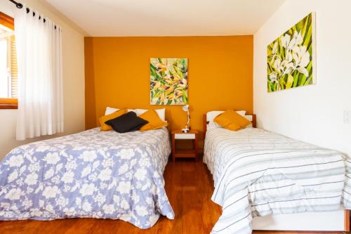 two beds in a room with yellow walls at Putini Pousada e Hotel by OYO in São Roque