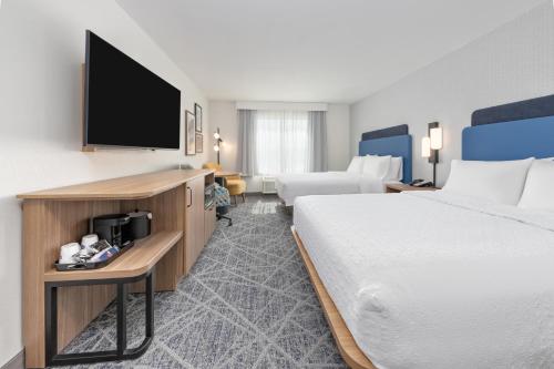 a hotel room with two beds and a flat screen tv at Hampton Inn & Suites by Hilton Little Rock Airport in Little Rock