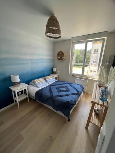 une chambre avec un lit bleu et une fenêtre dans l'établissement Le Bellevue Appartement, à Merlimont
