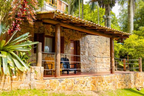 a stone house with a porch with a deck at Putini Pousada e Hotel by OYO in São Roque