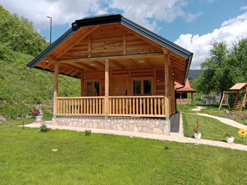 a large wooden cabin with a large porch at Holiday Lux Mokra Gora in Mokra Gora