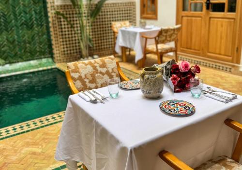 einen Tisch mit Platten und eine Vase mit Blumen darauf in der Unterkunft Riad Dar Timrad in Fès