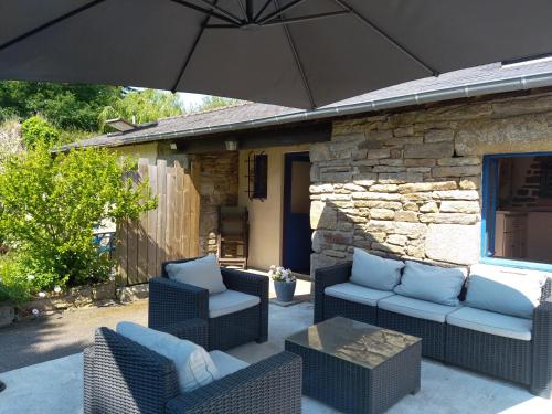 patio z 2 krzesłami i parasolem w obiekcie Chez Malika w mieście Bannalec