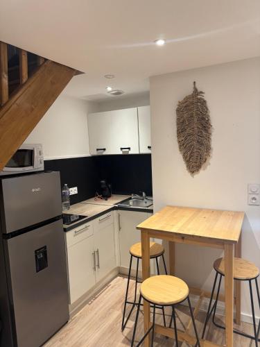 - une cuisine avec une table et quelques tabourets dans l'établissement La suite dorée, à Roubaix