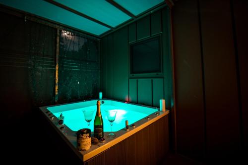 a bathroom with a tub with wine bottles and glasses at VRBA mobile house by the Kolpa river BIG BERRY Metlika in Metlika