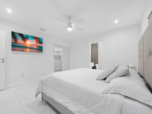 une chambre blanche avec un lit et un ventilateur de plafond dans l'établissement The Chill Sunny Casa Near Beaches, à Miami Lakes