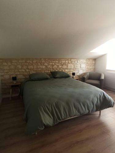 une chambre avec un grand lit et un mur en pierre dans l'établissement Gîte de charme à Loudun, à Loudun