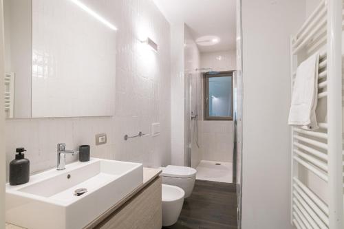 a white bathroom with a sink and a toilet at Palazzo La Cortesella - Modern Design & Central Location in Como