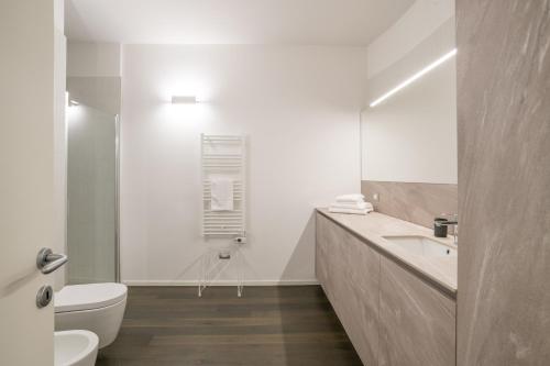 a white bathroom with a toilet and a sink at Palazzo La Cortesella - Modern Design & Central Location in Como
