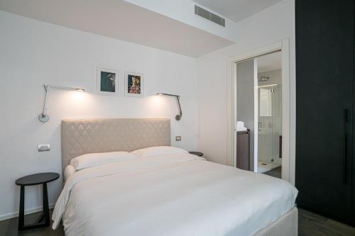 a bedroom with a large white bed and a table at Palazzo La Cortesella - Modern Design & Central Location in Como