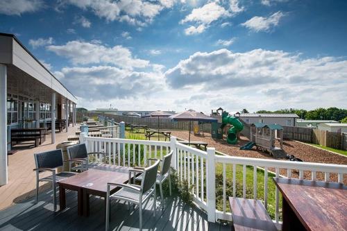 a balcony with tables and chairs and a playground at Crimdon Dene Caravan in Hart