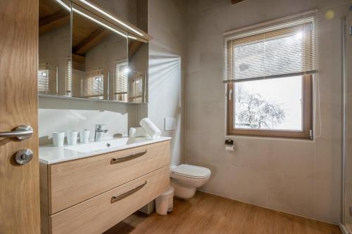 bagno con lavandino, servizi igienici e finestra di Resort Tirol am Wildenbach a Niederau