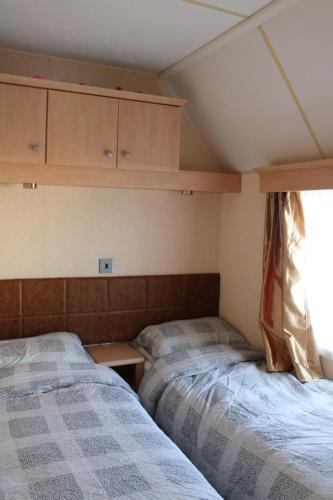 two beds in a small room with a window at Crimdon Dene Caravan in Hart