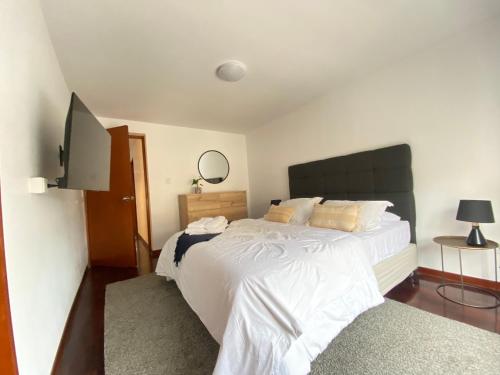 a bedroom with a large white bed and a flat screen tv at Vistamar Duplex in Lima
