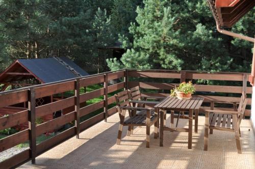 a wooden table and chairs on a deck with a fence at Wczasy na Kaszubach, balia, sauna, jezioro in Wąglikowice