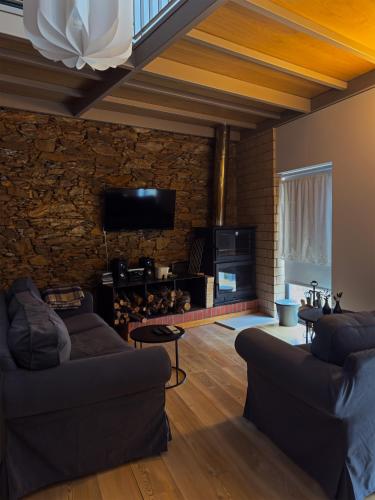 a living room with two couches and a stone wall at Alojamento Rural com Salamandra e AC - 10 min da Barragem do Sabor - Casa do Largo in Parada