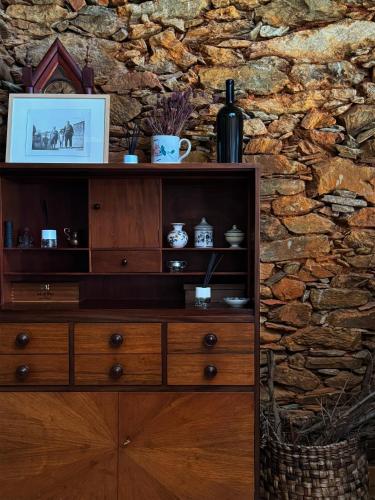 a wooden cabinet in front of a stone wall at Alojamento Rural com Salamandra e AC - 10 min da Barragem do Sabor - Casa do Largo in Parada