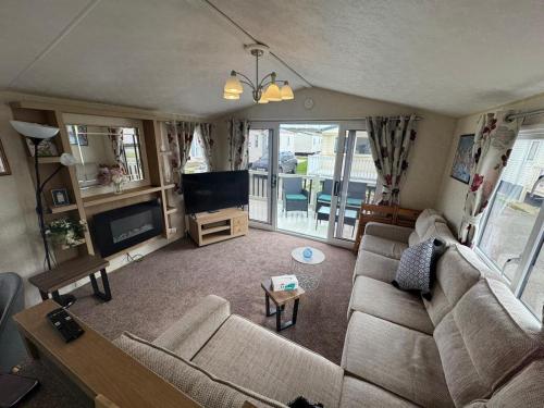 a living room with a couch and a tv at Golden Palm Resort - Willerby Avonmore - Coastal Caravan Breaks in Chapel Saint Leonards