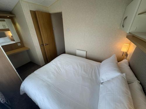 a bedroom with a bed with white sheets and pillows at Golden Palm Resort - Willerby Avonmore - Coastal Caravan Breaks in Chapel Saint Leonards